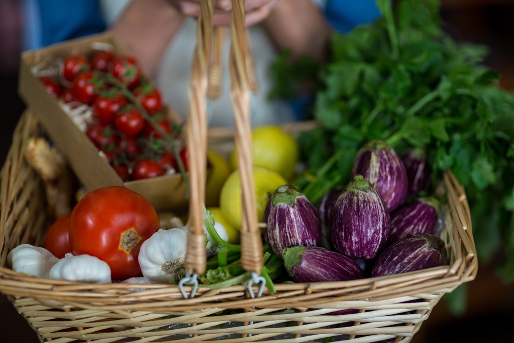 Close-up of female staff holding basket of vegetables in organic section of supermarket.jpeg